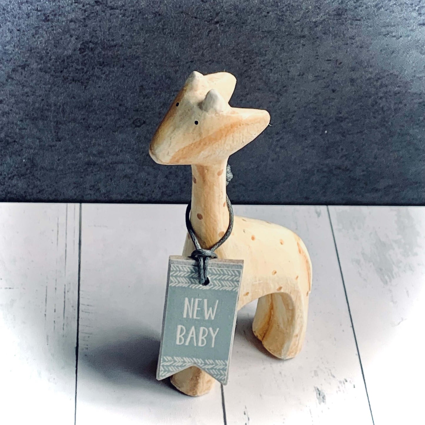 Small pale yellow giraffe with 'New Baby' tag around his neck. From Wickerhearts East of India gift collection.