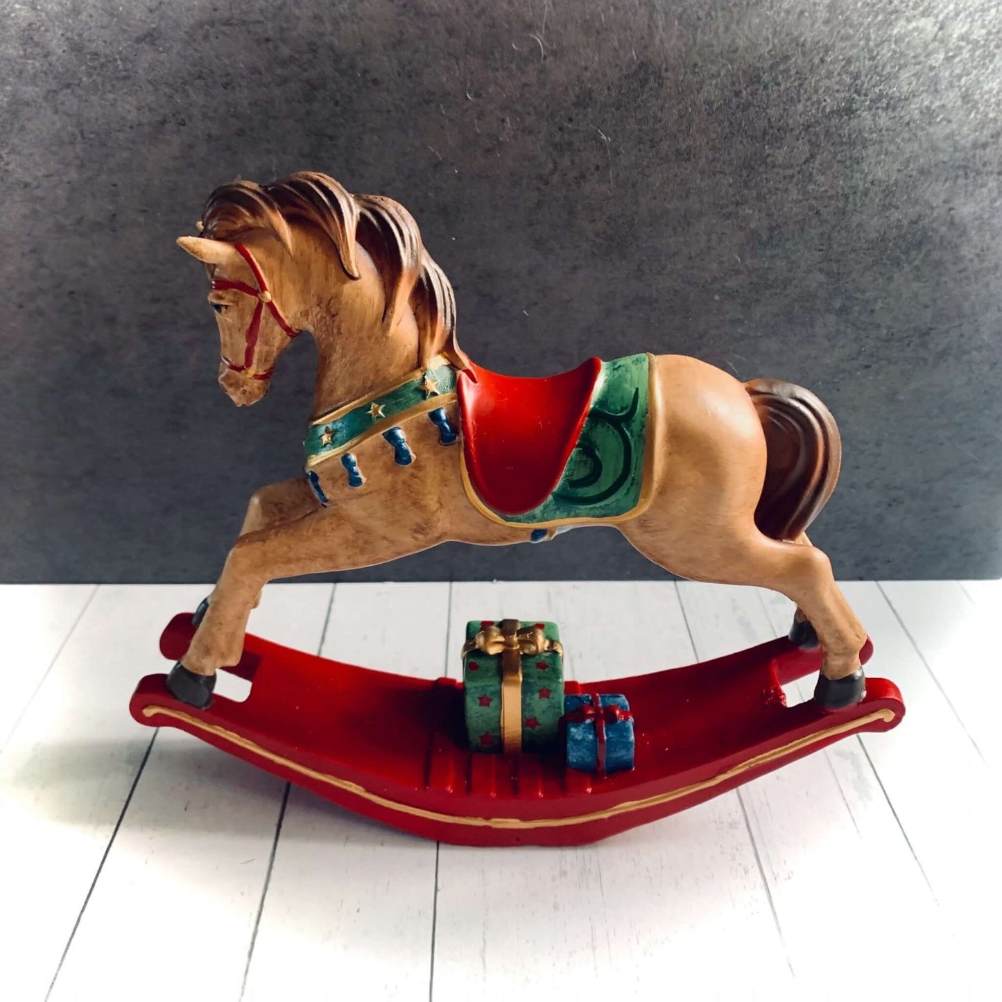 Elegant light brown rocking horse decoration with red saddle and gift parcels underneath. From Wickerhearts Christmas gift collection.