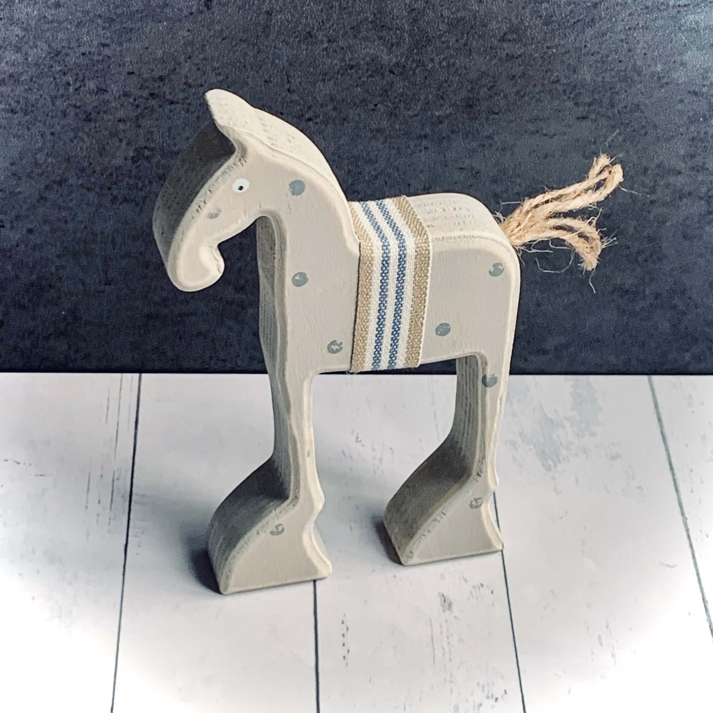 Small grey spotted wooden horse decoration, with striped blue and natural ribbon around the middle and jute string for it's tail.
From Wickerhearts East of India gift and decor collection.
