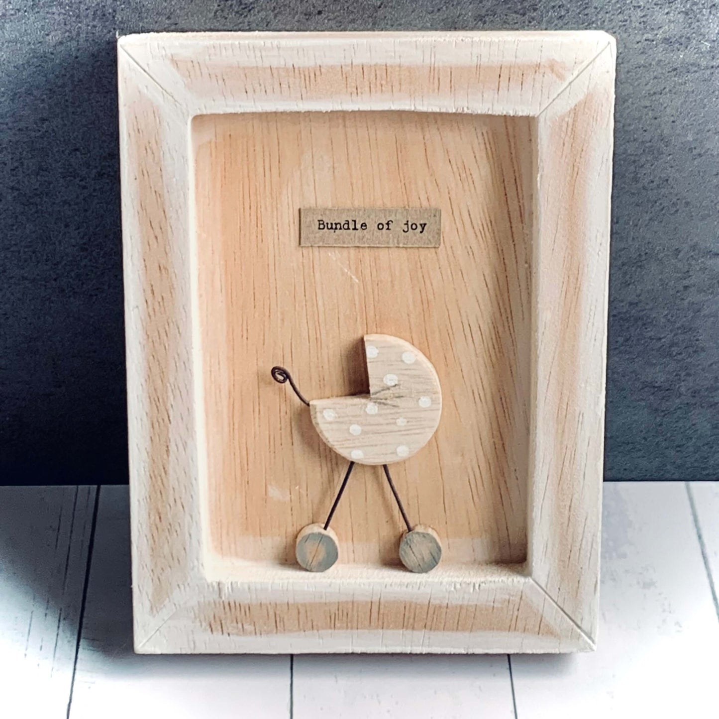 Wooden boxed frame in a neutral beige colour featuring a pram with the words 'Bundle of Joy'