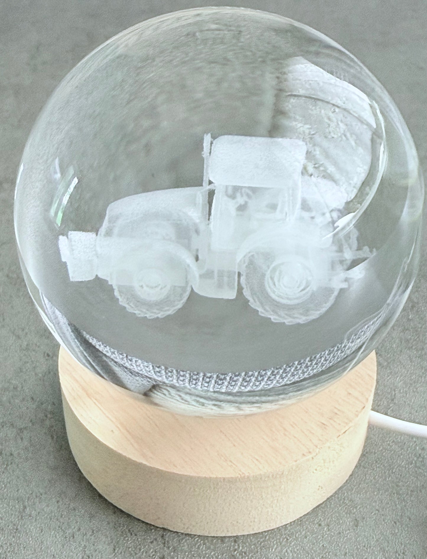 Glass sphere with engraved tractor design on a wooden base