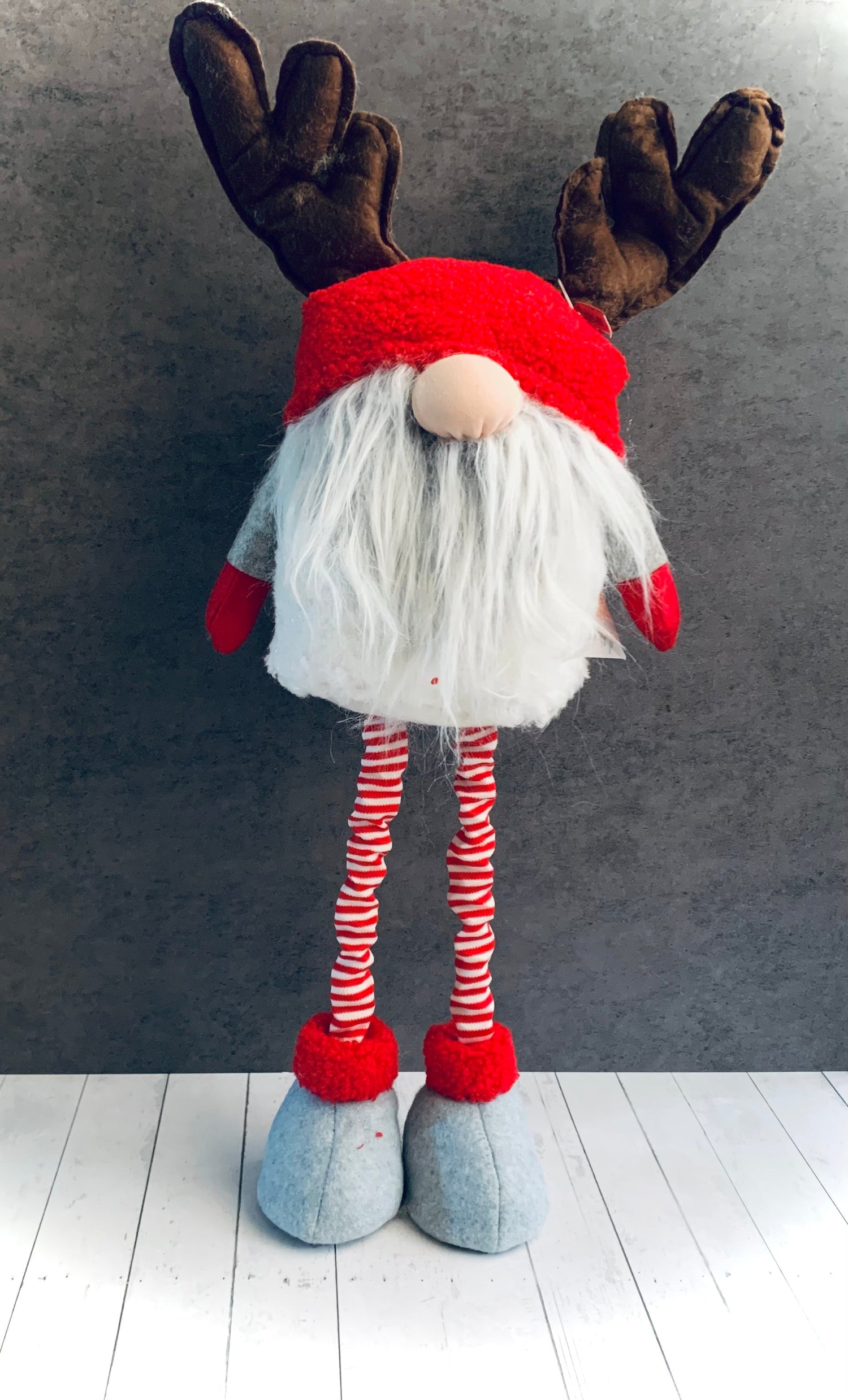 Image of tall red and grey fabric Gonk with brown antlers and red and white stripey extendable legs. From Wickerhearts Christmas gift collection.