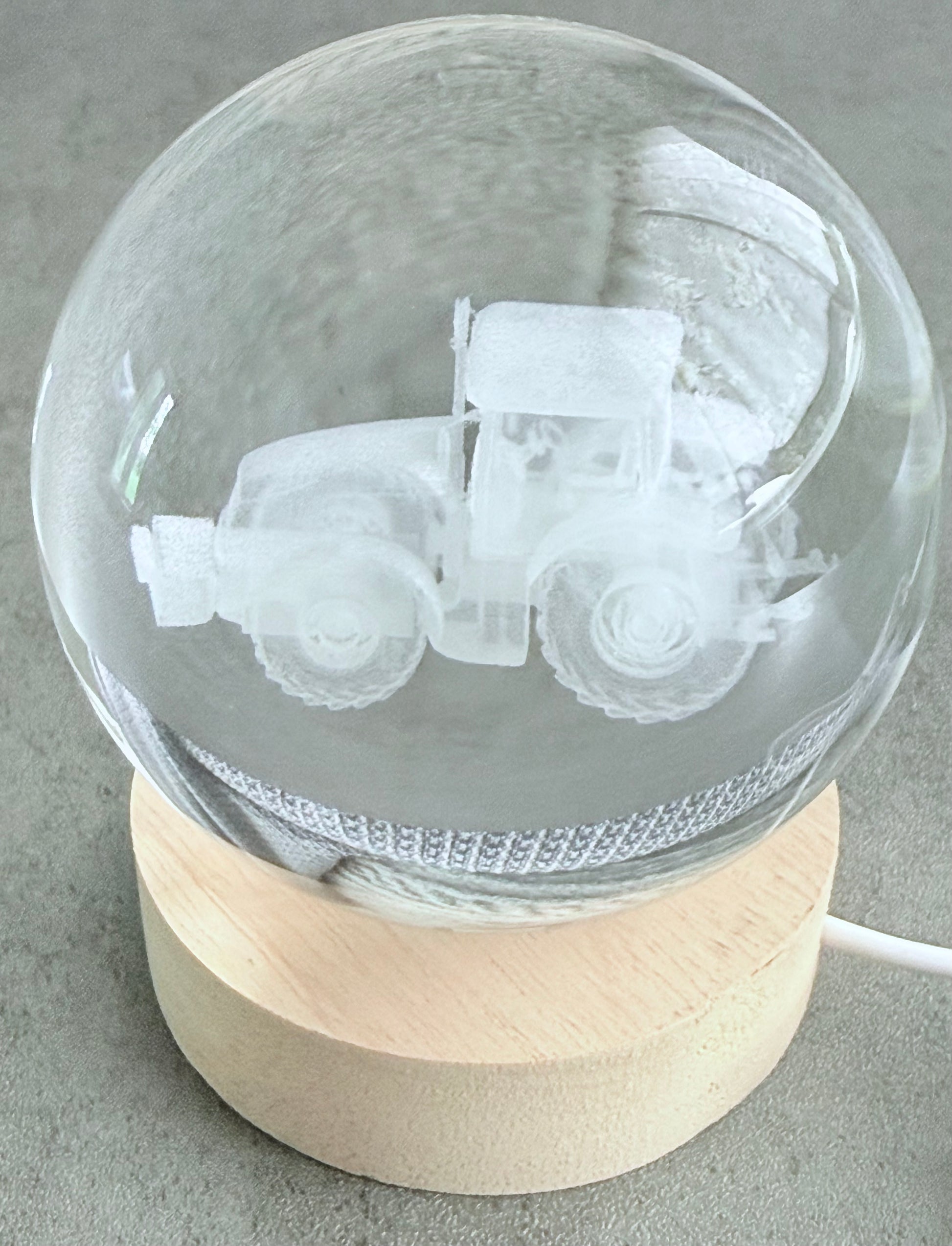 Glass sphere with engraved tractor design on a wooden base