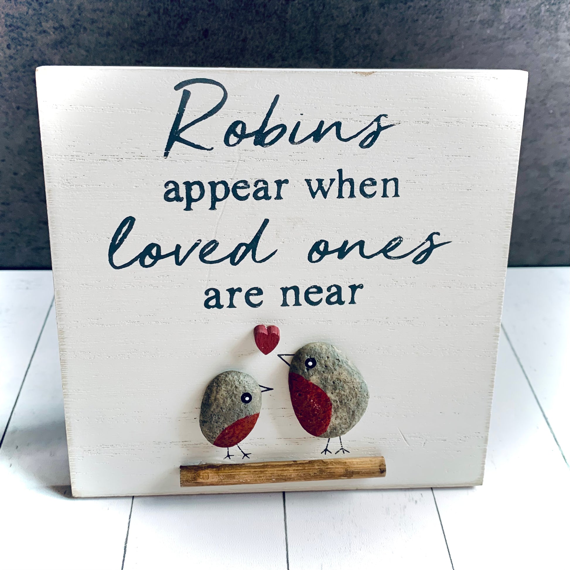 Close up view of square, white wooden small picture of 2 pebble robins on a branch with a love heart. The wording is 'Robins appear when loved ones are near'. This item is a bestseller from Wickerhearts Christmas and gift collection.