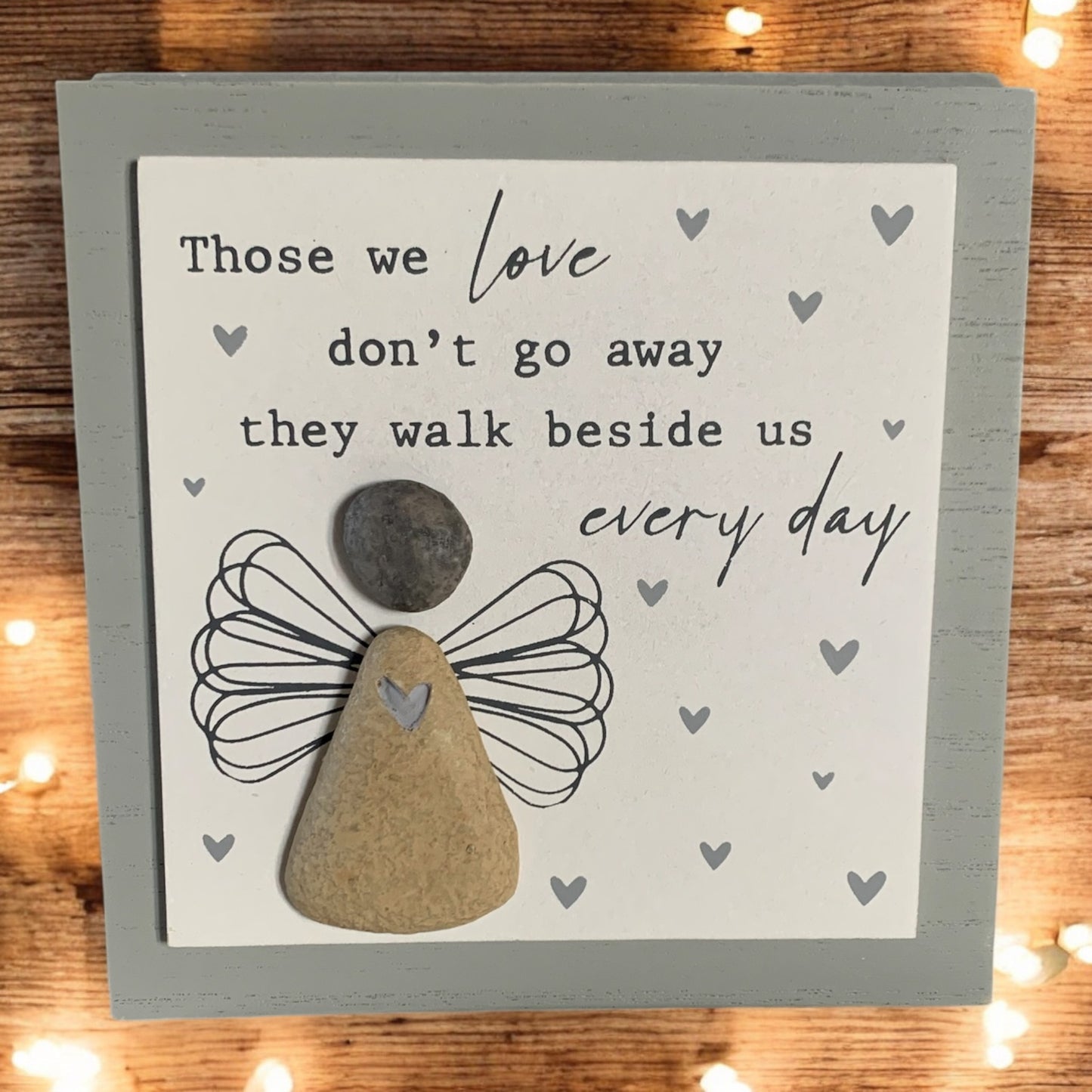 Front image of grey and white wooden memorial picture, featuring a pebble angel and the words 'Those we love don't go away they walk beside us every day'. From the Autumn and Christmas gift collection at Wickerhearts.