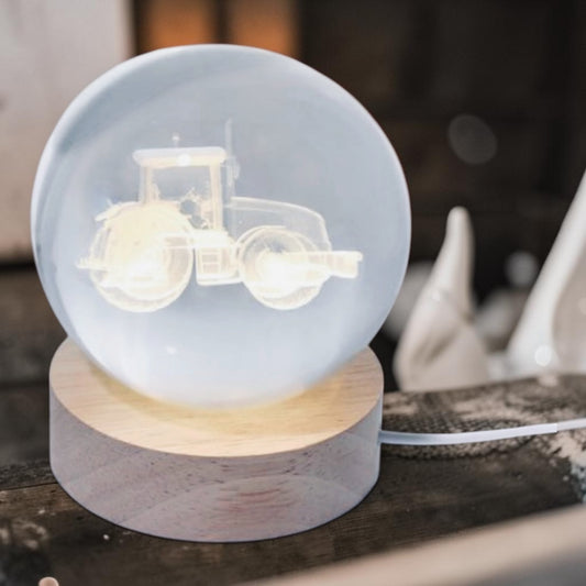 Glowing glass ball with tractor design on a wooden base